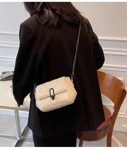 Détail d'un sac bandoulière matelassé beige crème avec chaîne et fermoir ovale