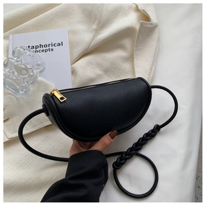Detail of black lychee grain leather saddle bag with woven rope strap and gold zipper