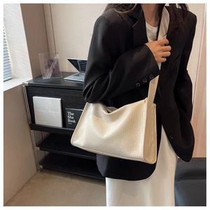 Dettaglio della borsa tote minimalista crema con trama a struzzo e tracolla strutturata chic
