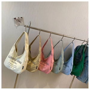 Detailed row of various colored canvas tote bags showing strap and side pocket
