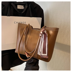 Detail of brown tote bag featuring white contrast stitching and a printed fashion scarf