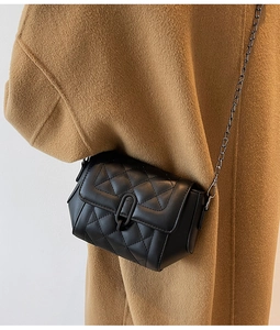 Détail d'un sac bandoulière noir matelassé avec boucle en métal et bandoulière chaîne