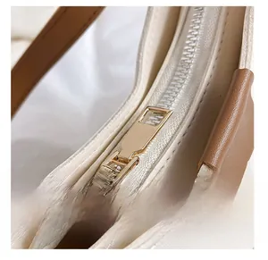 Close-up of smooth gold metal zipper on minimalist cream and brown shoulder bag
