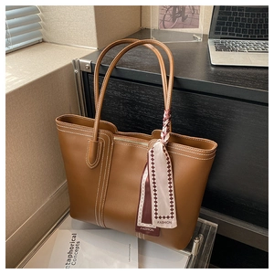 Detailed view of caramel tote bag with contrast stitching and decorative silk scarf