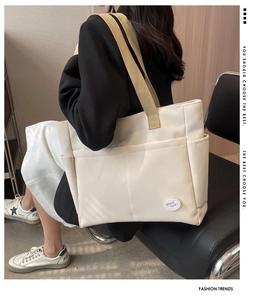 Detail of canvas tote bag showing side pockets and lucky patch on creamy white fabric