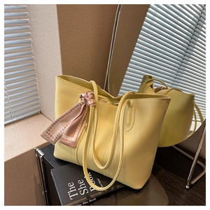 Detail of light yellow leather tote bag with a decorative pink fashion silk scarf on handle