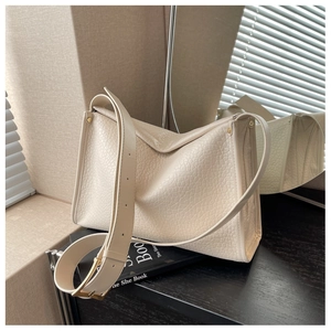 Dettaglio della borsa tote in pelle color crema con tracolla larga e fibbie dorate
