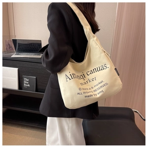 Detail of minimalist cream canvas tote bag with black typography and side woven label