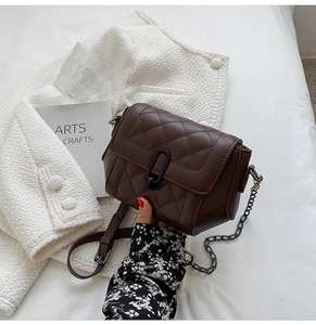 Détail d'un sac en cuir matelassé marron foncé avec fermoir en U et bandoulière chaîne