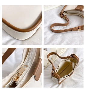 Detail view of the brown leather strap, gold hardware, and interior of the cream shoulder bag