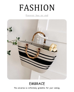 Detail of woven tote bag with striped pattern and natural bamboo handle hanging on door