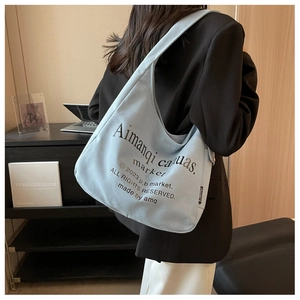 Detail of light blue canvas tote bag featuring stylish typography and side woven label