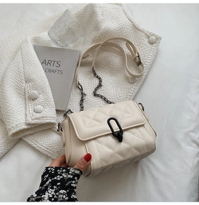 Détail d'un sac bandoulière matelassé crème avec une boucle en métal noir en forme de U