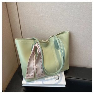 Detail of green tote bag with decorative geometric silk scarf and top zipper closure