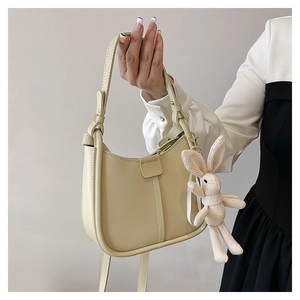 Detail of cream shoulder bag with vertical stitching and cute rabbit charm accessory