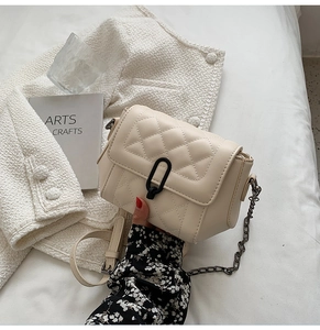 Détail d'un sac bandoulière matelassé crème avec fermoir ovale noir élégant