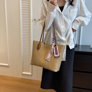 Detail of minimalist khaki tote bag with contrast brown handle and decorative fashion scarf