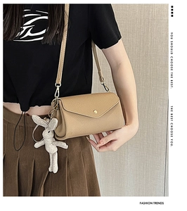 Detail of khaki square crossbody bag with lychee texture and woven rabbit pendant