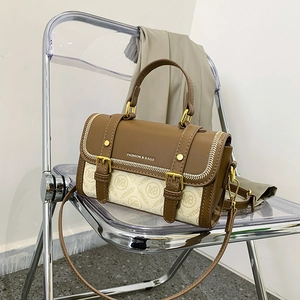 Borsa a tracolla monogramma marrone e beige con manico su una sedia moderna
