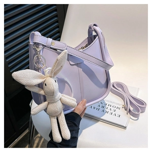 Detail of light purple leather handbag with white crochet rabbit charm and strap