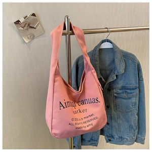 Detail of pink canvas tote bag featuring black lettering with blue denim background
