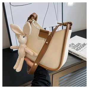 Detail of cream and brown PU leather handbag with a cute knitted rabbit pendant charm