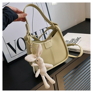 Detail of lime green shoulder bag with woven rabbit charm on a modern background