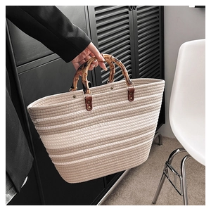 Detailed close-up of woven tote bag with natural bamboo handle and brown leather accents
