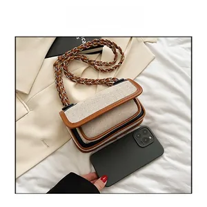 Mini crossbody bag with woven texture and leather trim next to a phone for size comparison