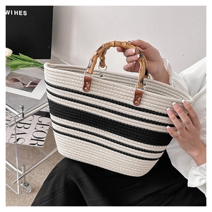 Detail of woven tote bag with natural bamboo handle and beige black striped pattern