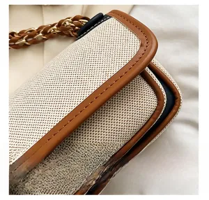 Detailed close-up of cream canvas fabric with brown leather trim and metal chain strap