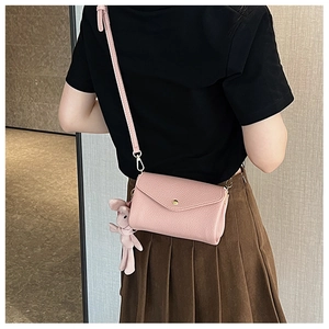 Close-up of a pink leather crossbody bag featuring a cute rabbit charm and metal clasp