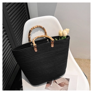 Detail of woven black tote bag featuring handcrafted bamboo handles and textured surface