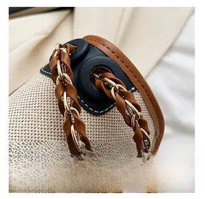 Detail of woven gold chain strap and brown leather trim on a vintage beige canvas bag