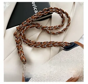Detailed macro view of the woven brown leather and gold chain shoulder strap on canvas bag
