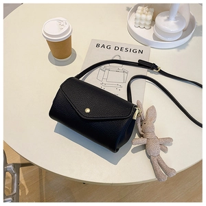 Close-up of black lychee texture crossbody bag with bunny charm and golden metal buckle