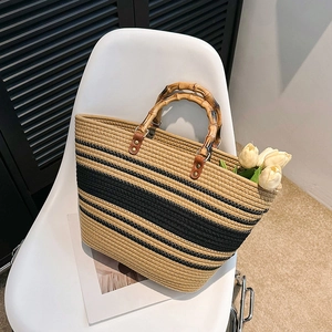 Handwoven straw tote bag with black stripes, bamboo handles, and spacious design