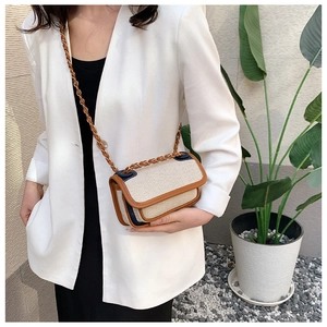 Detail of canvas shoulder bag with brown leather trim and metal chain strap