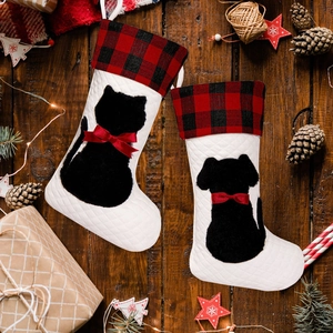Detail van gewatteerde kerstsokken met katten- en hondensilhouetten op houten achtergrond