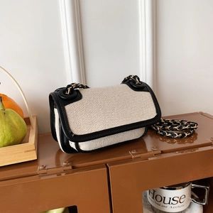 Retro canvas square bag with black leather trim and chain strap on a vintage metal cabinet