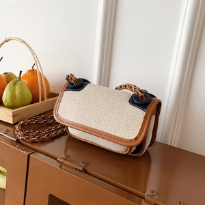 Retro canvas crossbody bag with brown leather trim and golden chain strap on a vintage counter