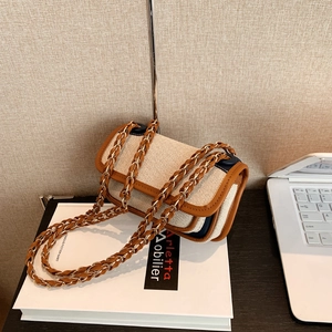 Chic beige woven small crossbody bag with brown leather trim and chain strap on desk