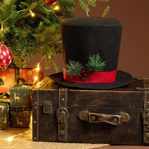 Close-up of black felt top hat tree topper with red ribbon and pine needle berries