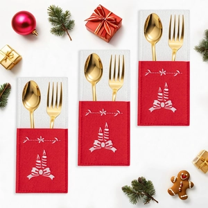 Detail of red felt Christmas cutlery holders with white embroidery and festive decor
