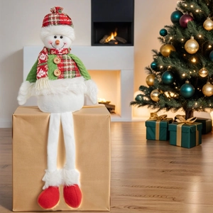 Detail of plush snowman decor with plaid hat and green sweater by a festive fireplace