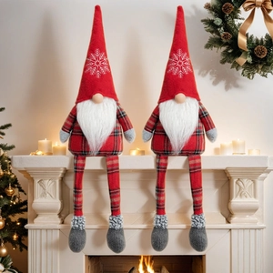 Close-up of red Christmas gnomes with snowflake hats sitting on a festive white fireplace