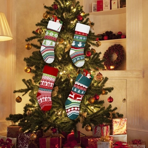 Set of 4 festive knitted Christmas stockings with reindeer and snowman on a tree