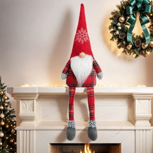 Close-up of Christmas gnome plush with long legs and snowflake hat on fireplace