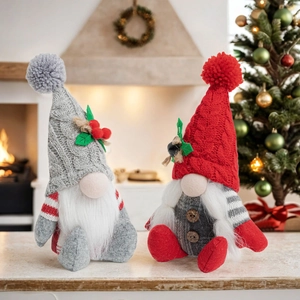 Close-up of knitted Christmas gnomes with long beards by a warm festive fireplace