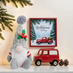 Close-up of a Christmas gnome with a grey knitted hat, holly leaves, and white beard decoration